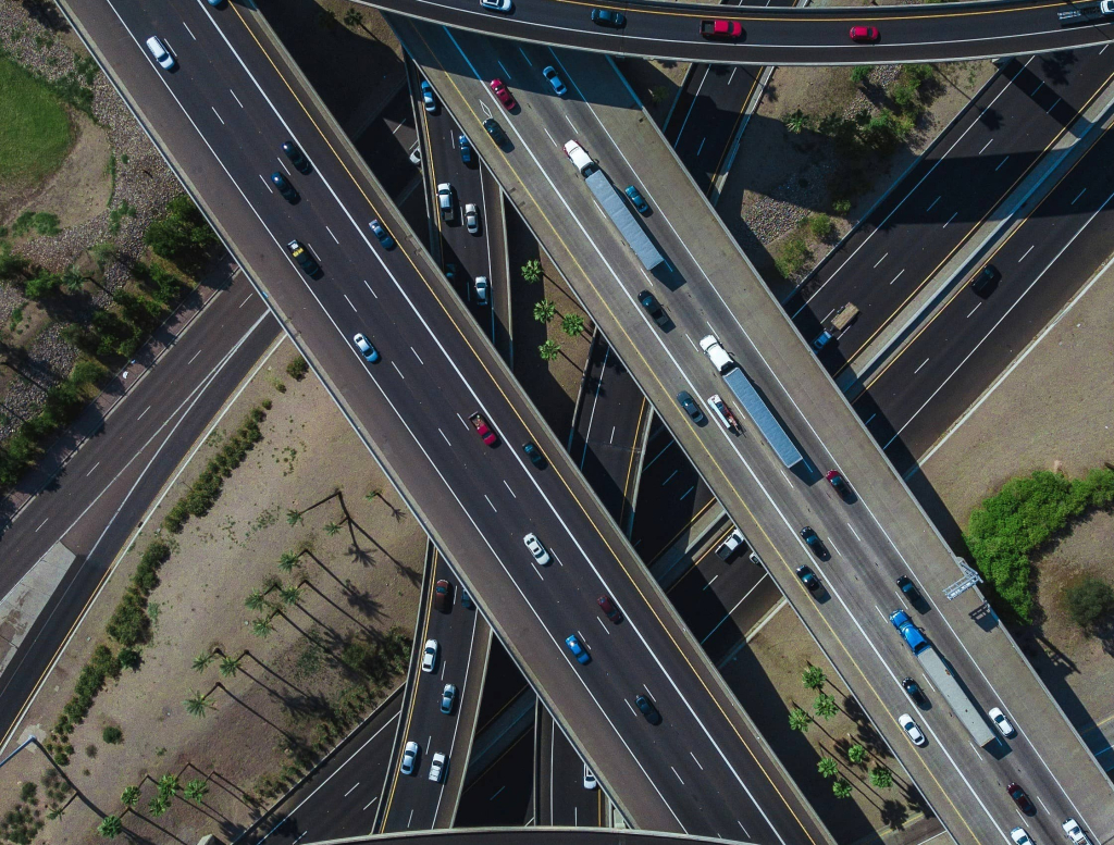 Vista aérea de um complexo de rodovias e viadutos, com diversos carros circulando em diferentes vias.